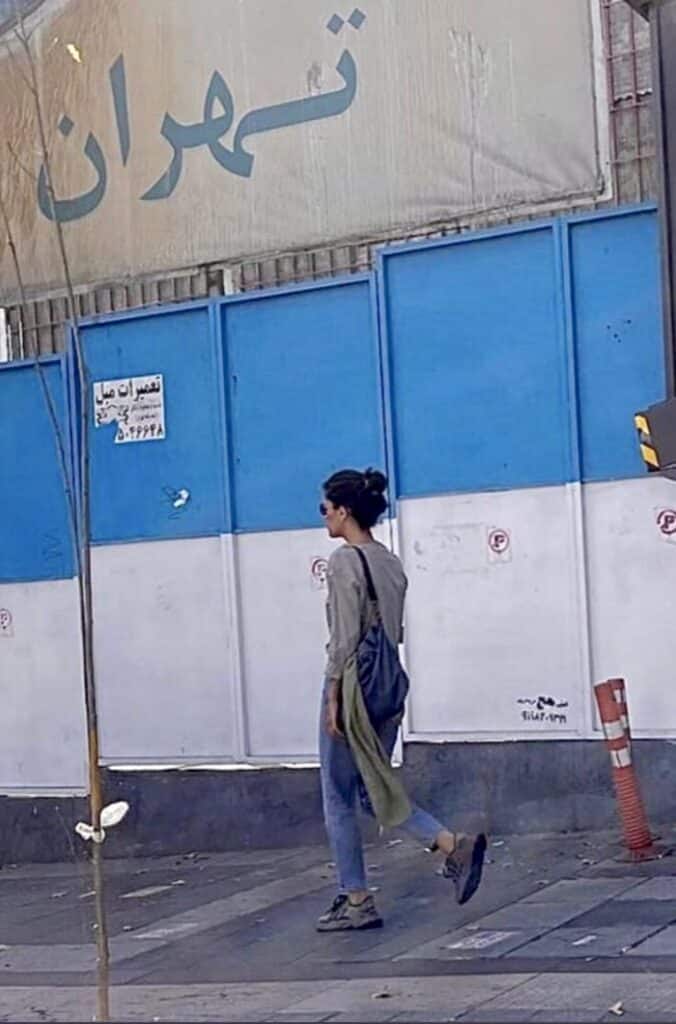 Dopo le proteste in Iran una giovane cammina per le strade di Teheran con il velo appeso allo zaino